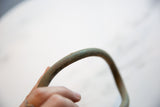 Aged patina and handmade surface texture of the curved African bronze artifact.