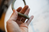 The antique bronze artifact held in hand, showing its scale and handmade texture.