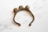 The handmade craftsmanship and aged patina of a vintage African bronze bell bracelet.