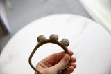 The three rounded bronze bells on the vintage cuff bracelet, showing their pitted, textured surface.