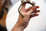 Vintage African bronze bell cuff bracelet held in hand to show its scale and form.