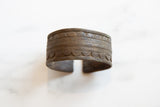 The open back and aged patina of a hand-etched antique African bronze cuff bracelet.