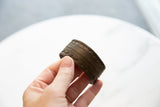 Antique African bronze cuff with etched patterns held in hand to show scale and detail.