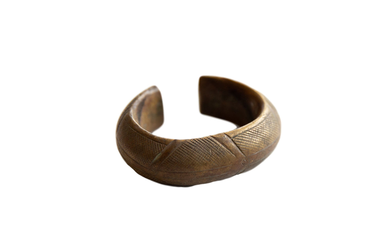 Antique African bronze cuff bracelet with etched geometric patterns and a time-softened patina.