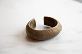 Angled view of a collectible African bronze cuff bracelet highlighting its etched geometric details.
