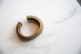 Aged patina and geometric details on the open shape of an antique bronze cuff.