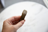 The solid, weathered profile of a striped antique African bronze cuff bracelet held in hand.