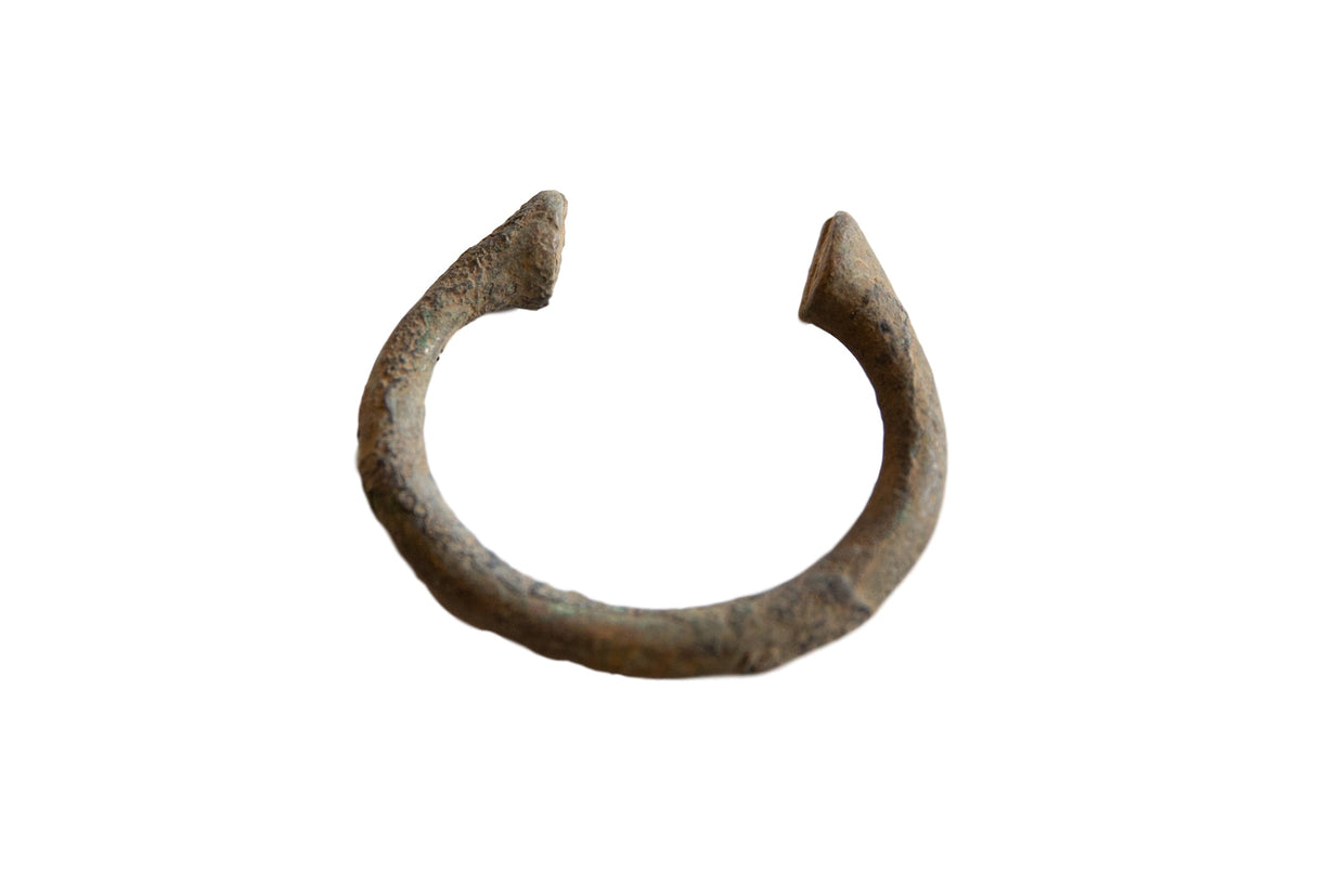 Collectible antique African bronze manilla bracelet with textured green-brown patina.