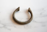 Close-up of the antique bronze cuff bracelet end, showing its rough texture and rich patina.