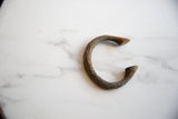 Textured surface and earthy patina of the antique bronze alloy manilla bracelet.