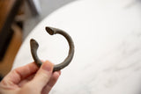 Hand-held view of the curved antique bronze manilla, showcasing its rich, aged patina.