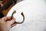 Hand holding the bronze alloy manilla cuff, revealing its rustic texture.