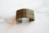 Side profile of a collectible bronze cuff showing its aged patina and handcrafted linear texture.