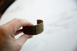 Antique bronze African cuff held in hand to show its scale and textured patina.