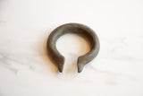 The unique C-shape and textured patina of an antique African bronze currency bracelet.