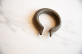 Handcrafted tapered ends of the antique bronze cuff showing a dark, time-softened patina.