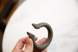 Angled view of the antique bronze cuff showing its C-shape and time-softened patina.