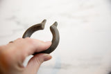 Antique bronze cuff held in hand, showing its C-shape and aged, textured patina.