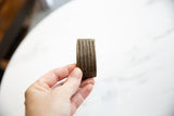Hand holding the antique African bronze cuff, showing its scale and grooved stripe design.