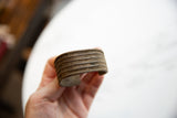The aged bronze patina and ribbed horizontal stripes of an antique African cuff.