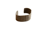 Antique African bronze cuff bracelet with a wide, textured stripe design and aged patina.
