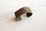 Handcrafted stripe details and aged patina on a collectible African bronze cuff.