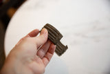 Collectible antique African bronze cuff held to display its ridged texture and dark patina.
