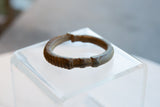 Side view of an antique bronze cuff showing its open design and textured geometric details.