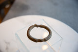 The handcrafted form and ridged geometric detailing of an antique African bronze cuff.
