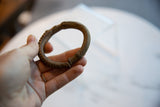 Antique African bronze cuff held to display its rounded shape and textured surface.