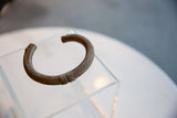 Curved profile of an antique African copper bracelet with hand-etched geometric patterns.