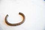 Angled view of the antique African copper cuff showing its open shape and dark, aged patina.