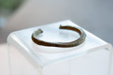 Side profile of the antique bronze cuff, showing its hand-carved geometric details.