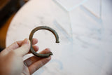 A hand holds the antique bronze cuff, showing its scale and aged patina.