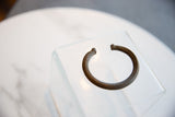 An antique African bronze striped cuff bracelet, angled to show its form and finish.