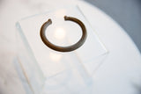 Antique bronze cuff bracelet with a time-softened patina, shown at an angle.