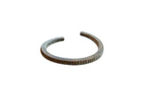 Antique African bronze cuff bracelet with a striped texture and dark, aged patina.