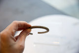 The curved profile and hand-worked striped texture of an antique African bronze cuff.