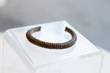 Profile of an antique African bronze cuff showing its ribbed design and rich patina.