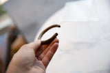 Antique striped bronze bracelet held in hand showing its curved form and texture.