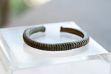 Side profile of the antique bronze cuff highlighting its handcrafted striped texture.