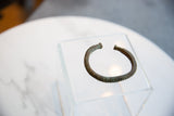 Angled view of the antique bronze cuff showing its striped texture and aged patina.