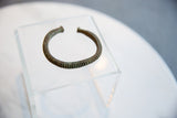 The hand-worked craftsmanship of a striped antique African bronze cuff with a deep patina.