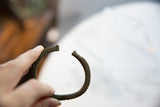 A view showing the handcrafted terminals and ridged exterior of the bronze cuff.