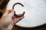 Antique African bronze cuff bracelet with notched edges, held to show its curved form.