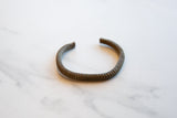 Angled view of the antique African bronze cuff's textured stripes and aged patina.