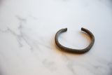 Full perspective of the antique bronze striped cuff, showing its open form.