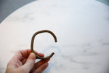 Antique African bronze cuff bracelet with striped texture held in hand.