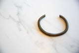 Handmade African bronze cuff bracelet showing its aged patina and curved form.