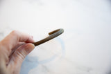 Profile view showing the handcrafted striped texture of the antique bronze cuff.